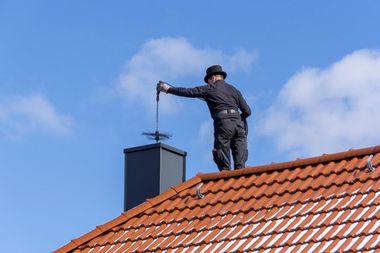 Man on top of a room cleaning a chimney