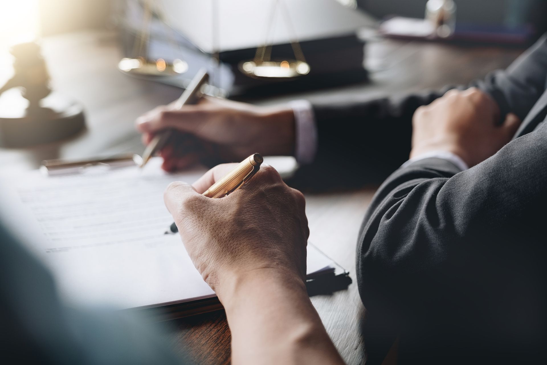 Hands writing on papers during a business meeting at a table