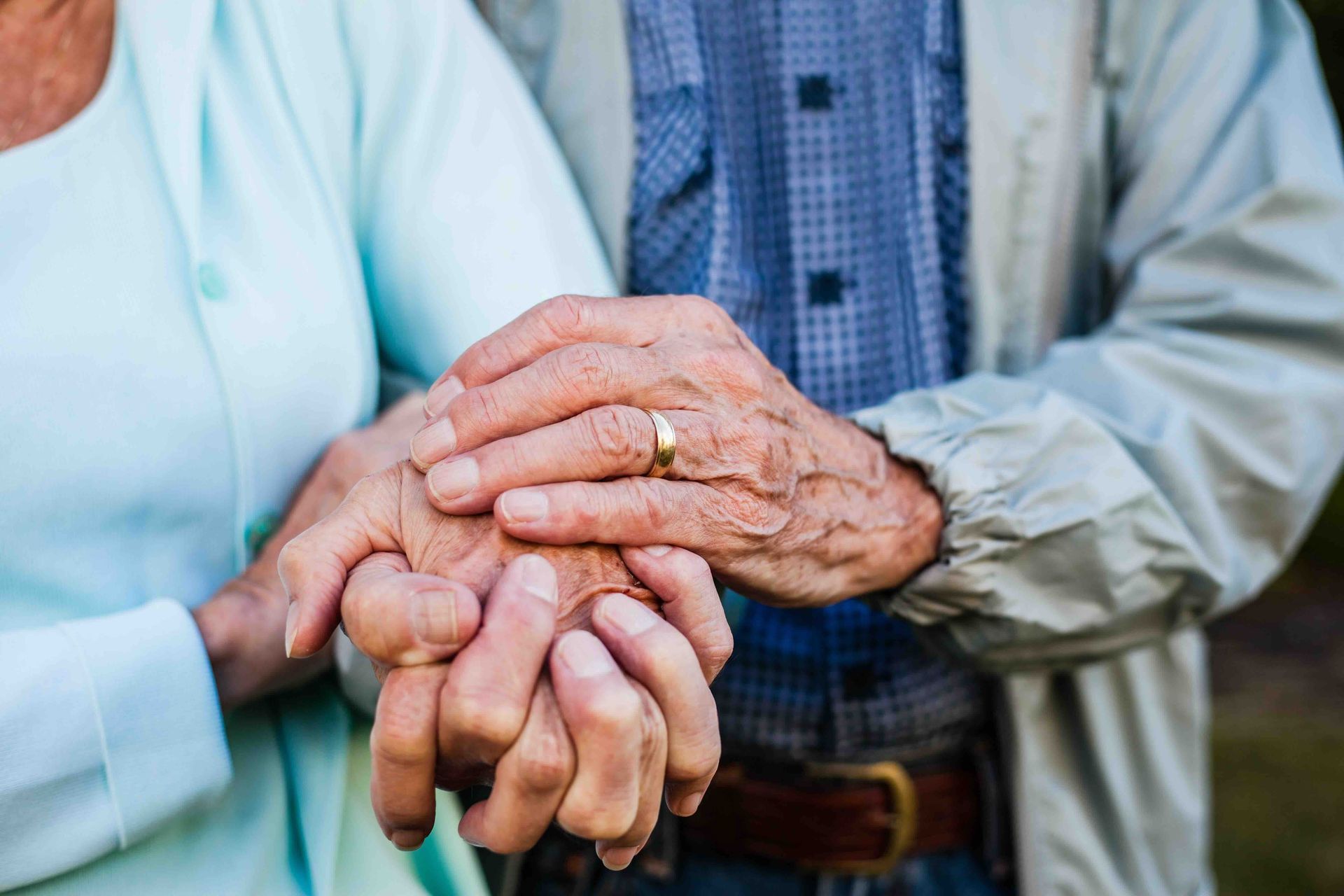 a man and a woman are holding hands and the man has a wedding ring on his finger .