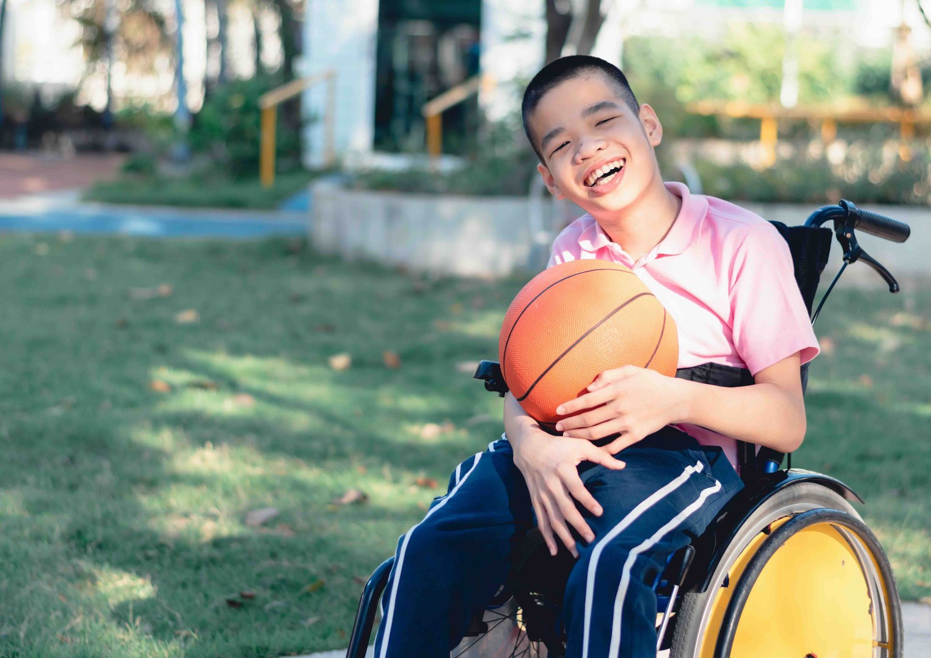 A young boy in a wheelchair is holding a basketball.