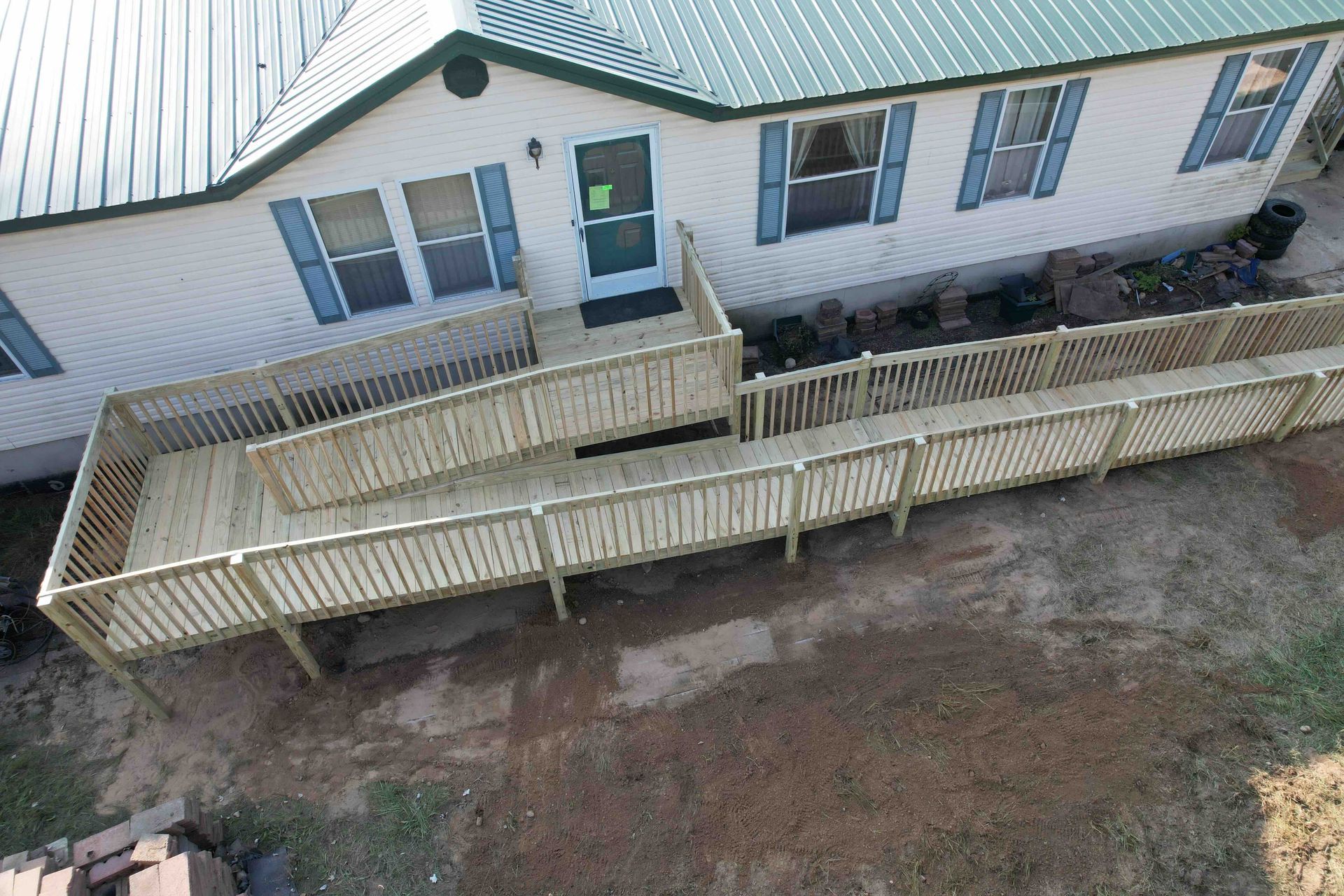 An aerial view of a mobile home with a wooden deck and ramp.