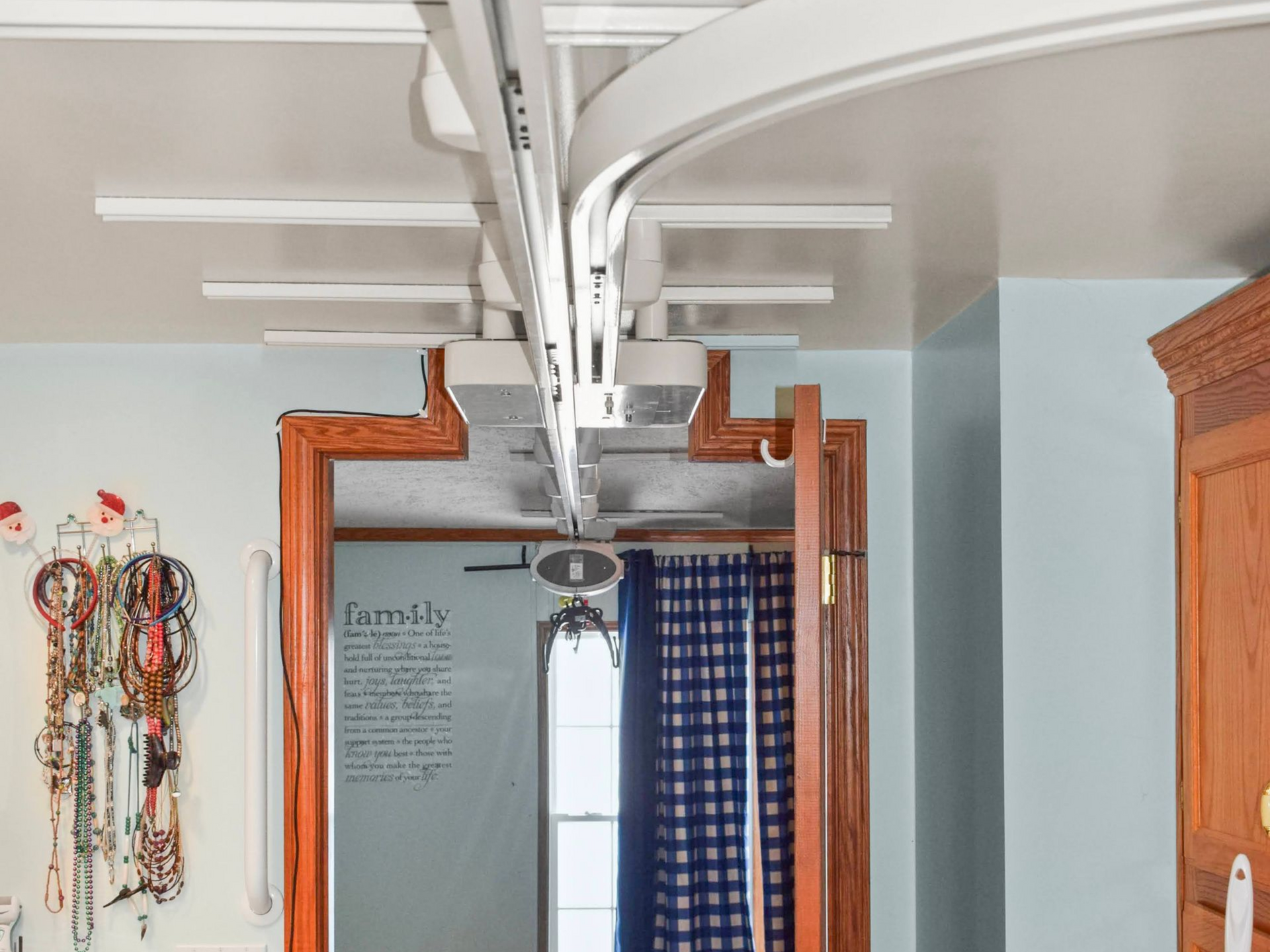 Ceiling-mounted track lift system curves above a doorway. White track and supports.