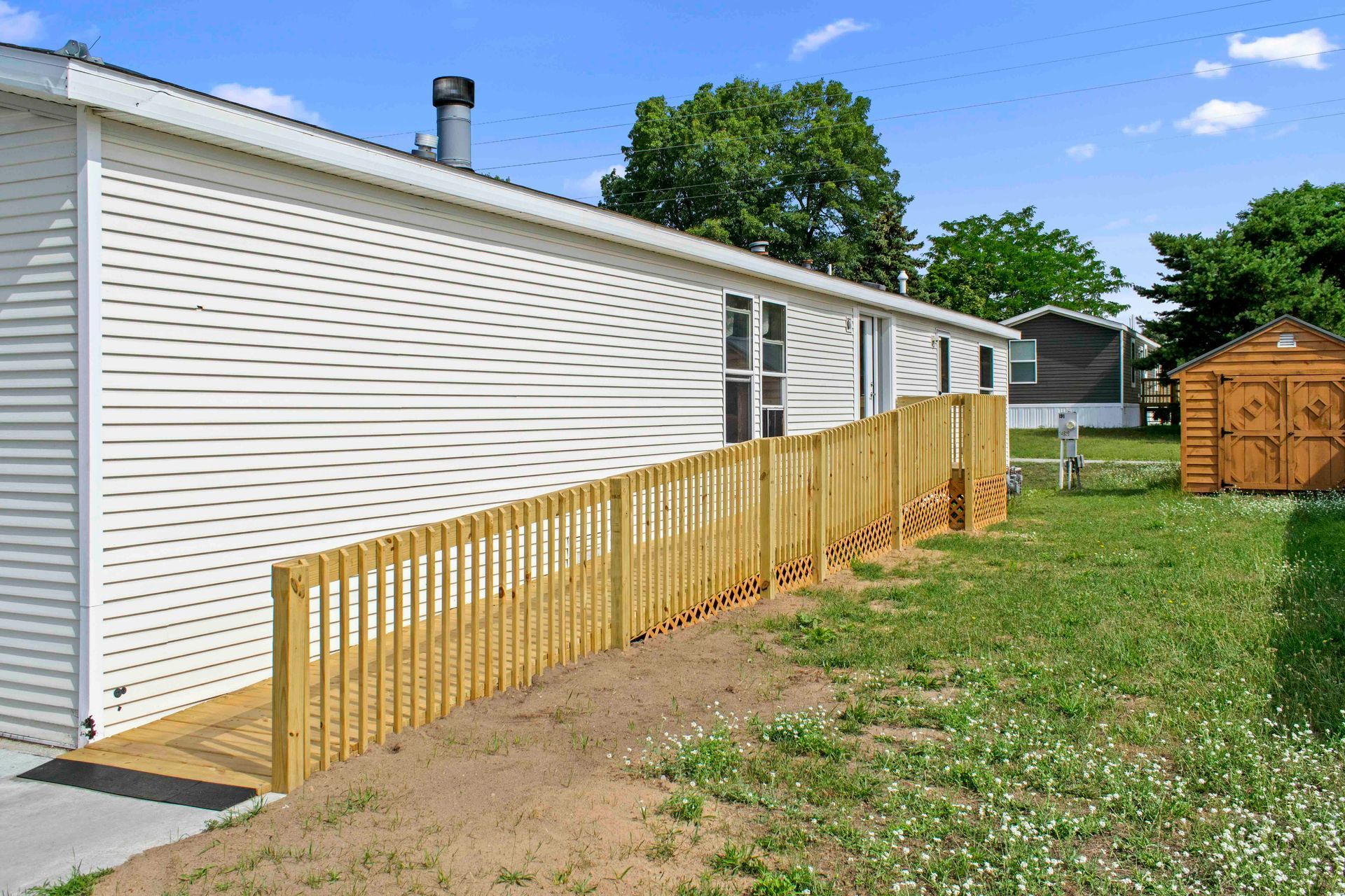 A mobile home with a wooden fence and ramp in front of it.