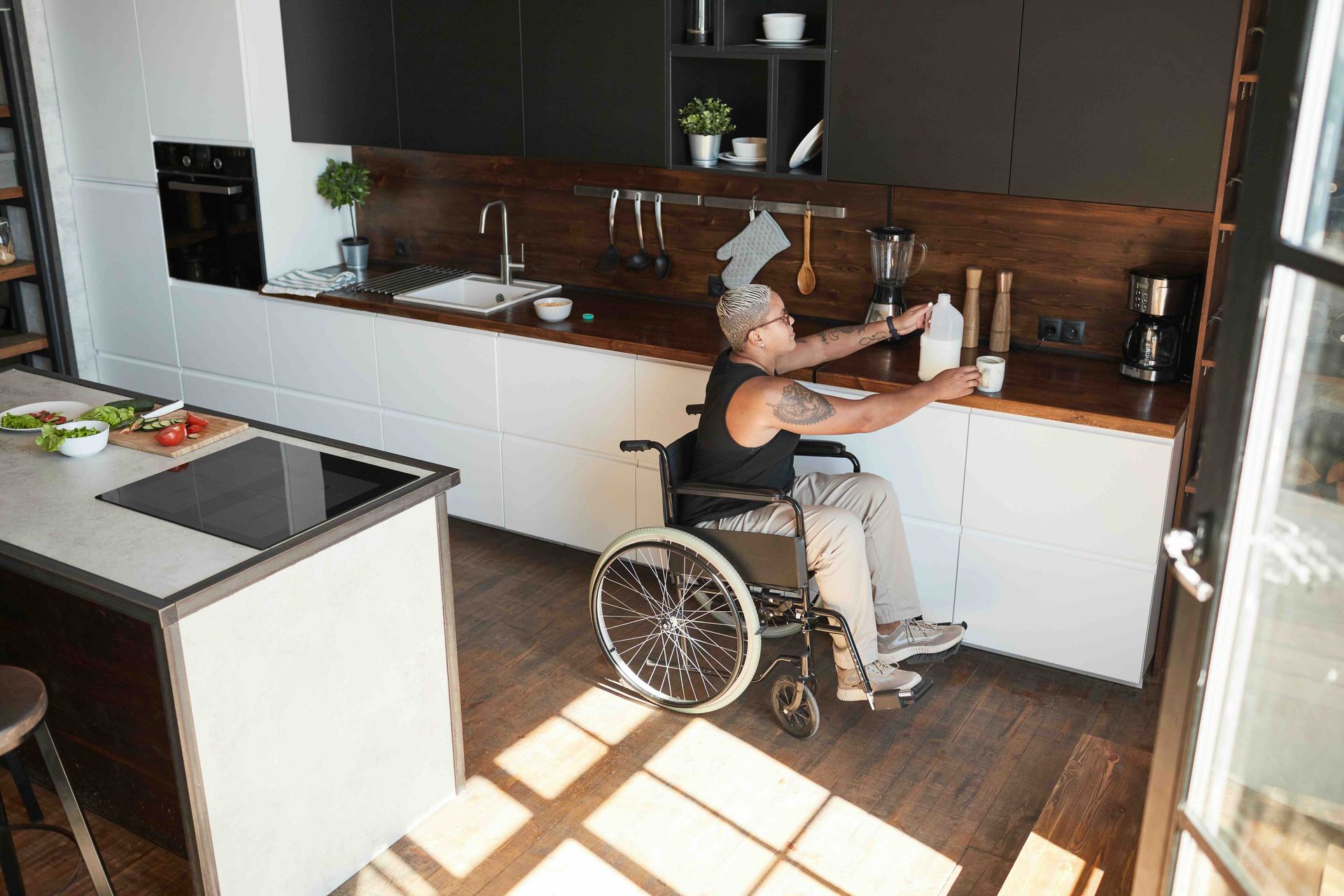 A person in a wheelchair is cleaning a kitchen counter.