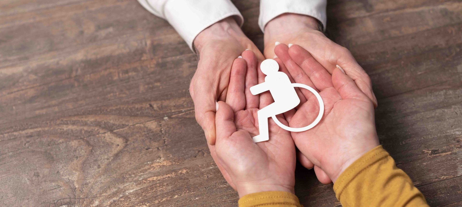 A person is holding a paper cut out of a person in a wheelchair.