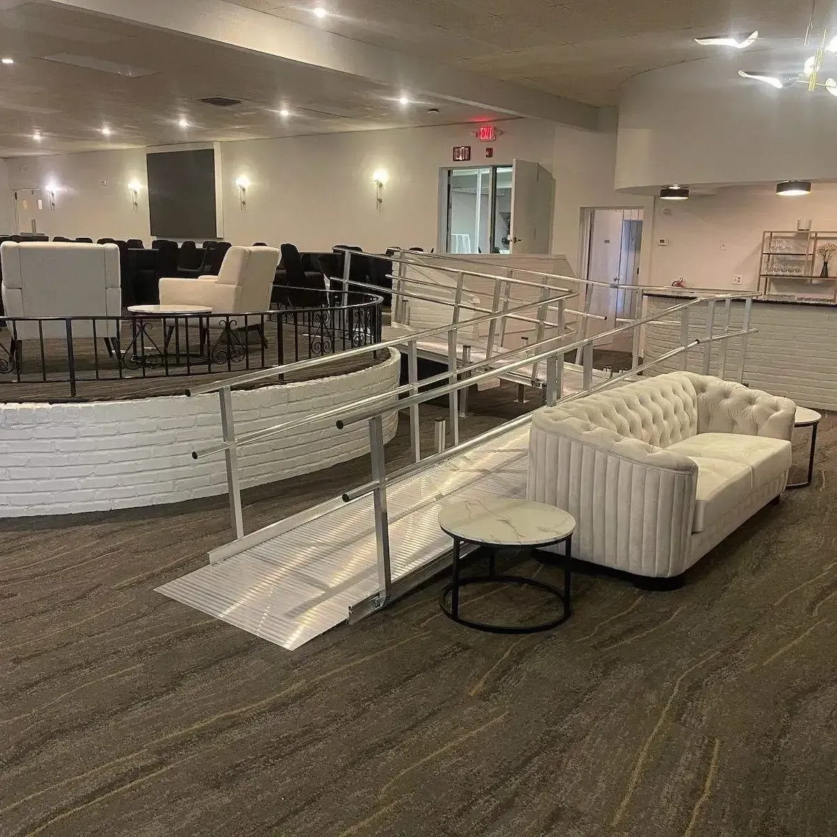 A wheelchair ramp at an event with a couch and end table next to it.