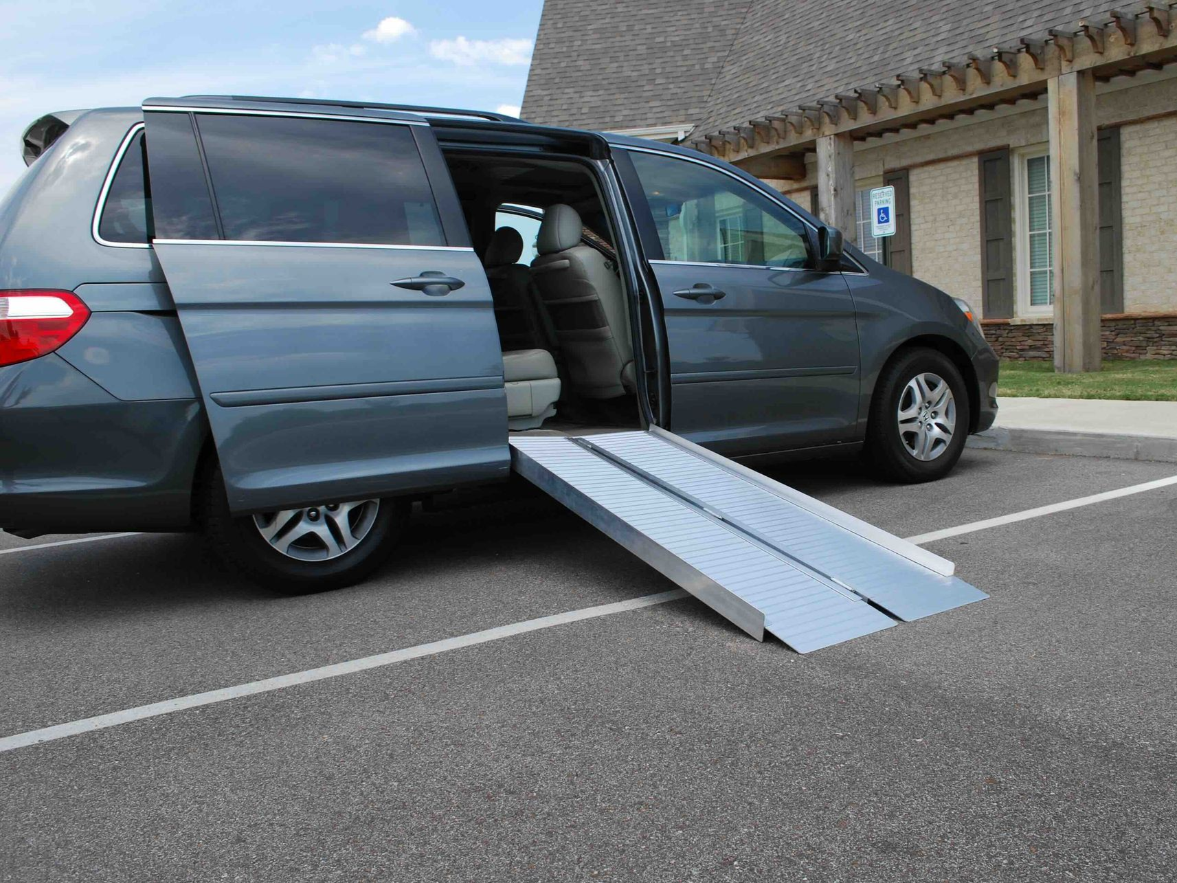 Gray minivan with deployed ramp in a parking space.