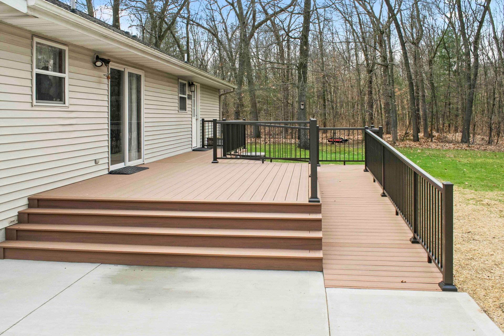 Exterior view of a house with a deck featuring steps and a ramp. Brown deck boards and railings.