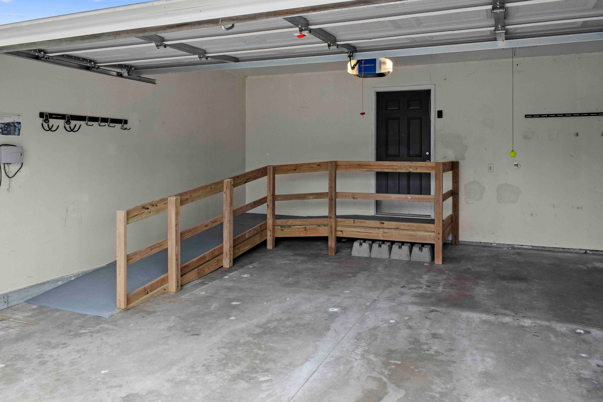 An empty garage with a wheelchair ramp and a wooden railing.