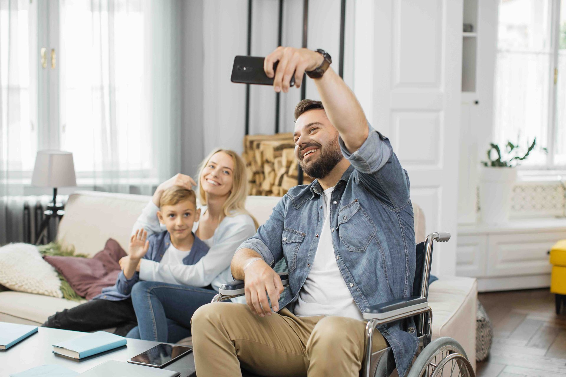 A man in a wheelchair is taking a selfie with his family.