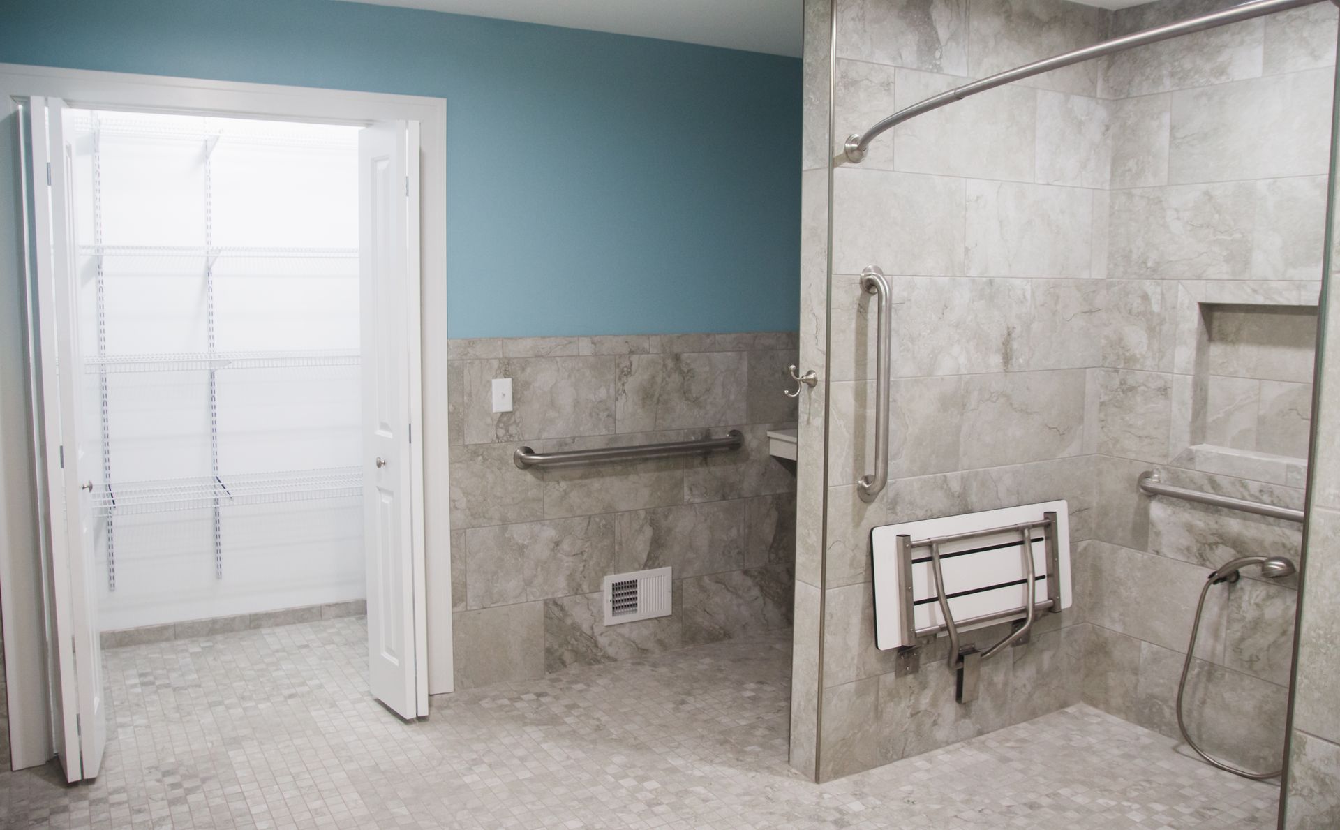 Accessible bathroom with roll-in shower, grab bars, and white door against a blue wall