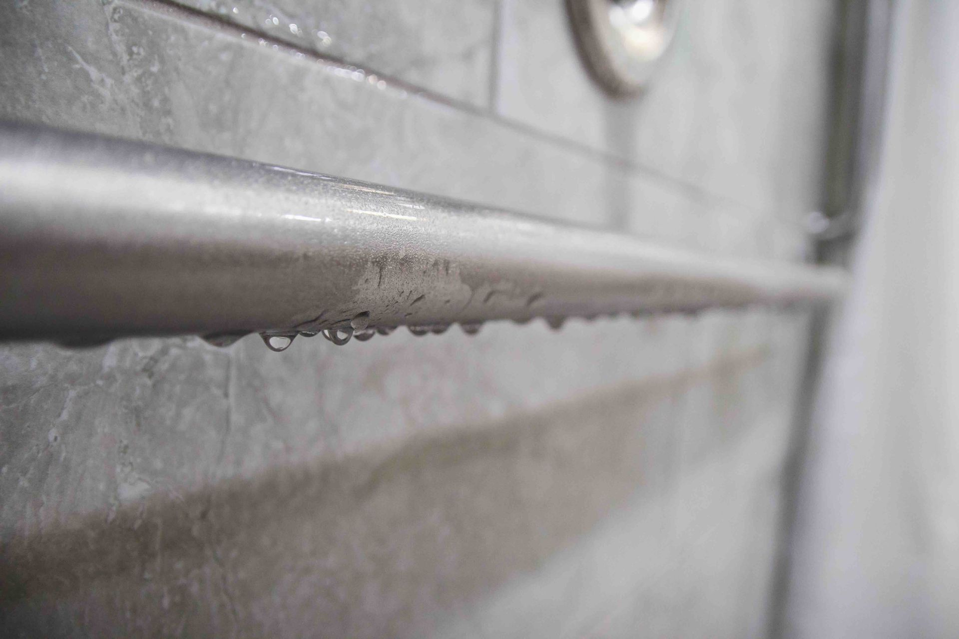 a close up of a shower rail with water drops on it.