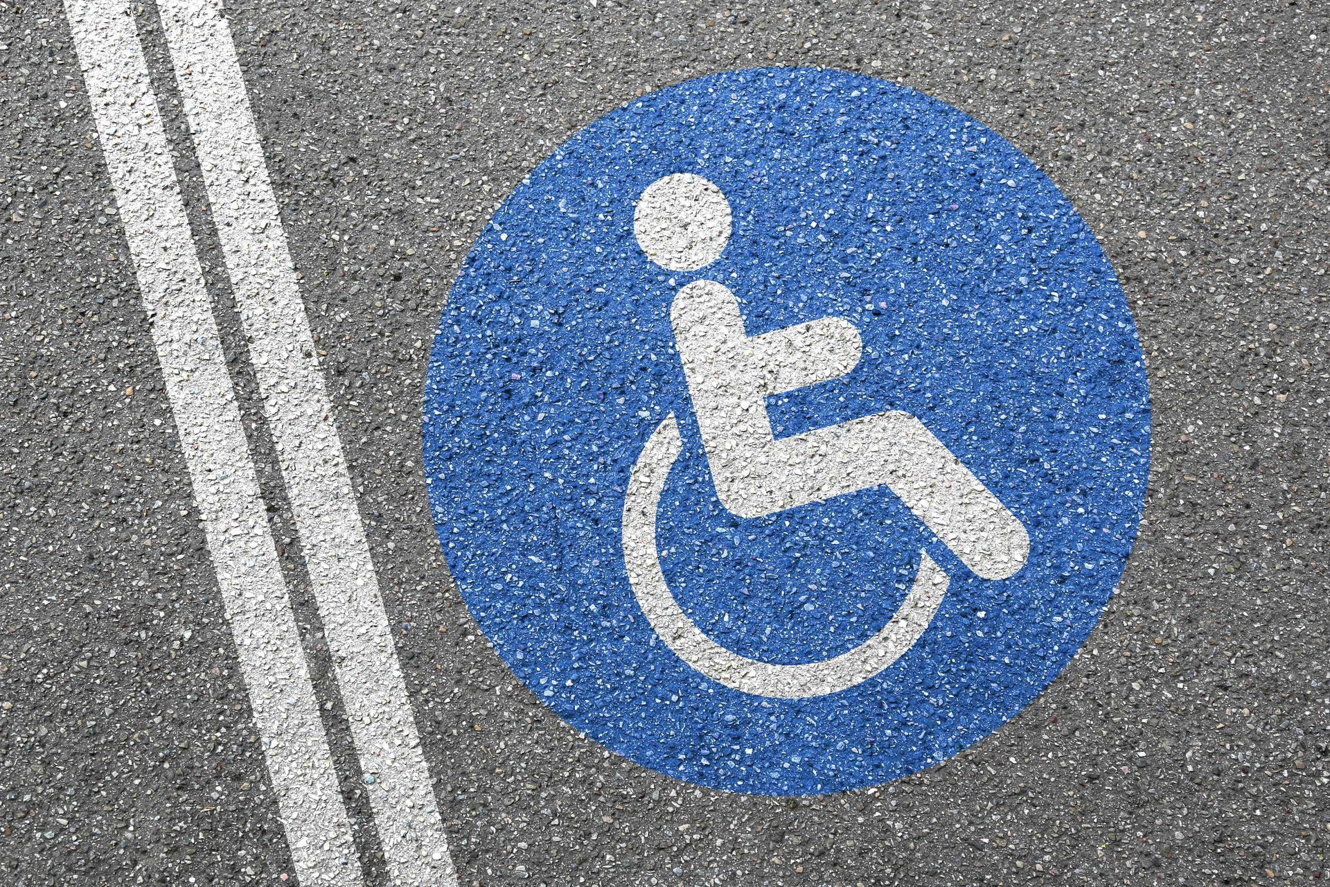 Blue and white handicap symbol painted on asphalt with double white lines.
