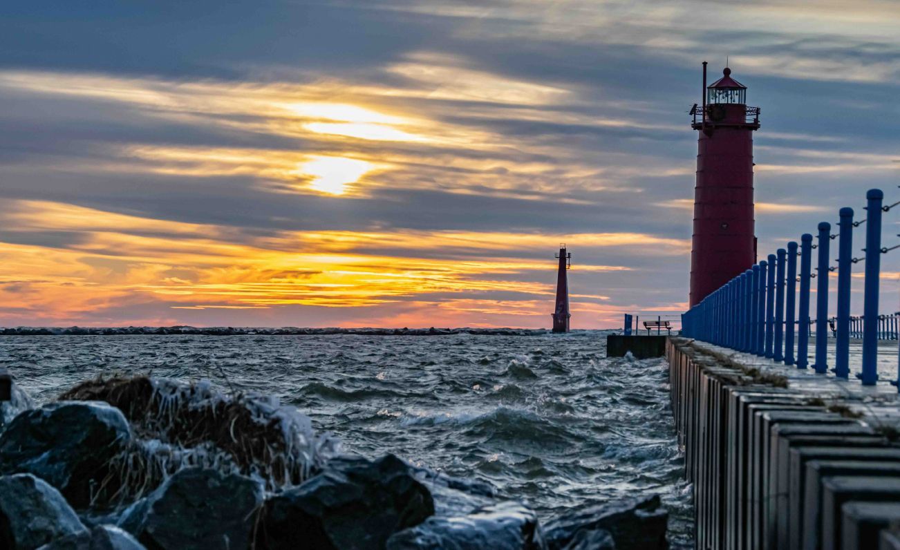 A lighthouse in Muskegon, Michigan on the shore of Lake Michigan at sunset.