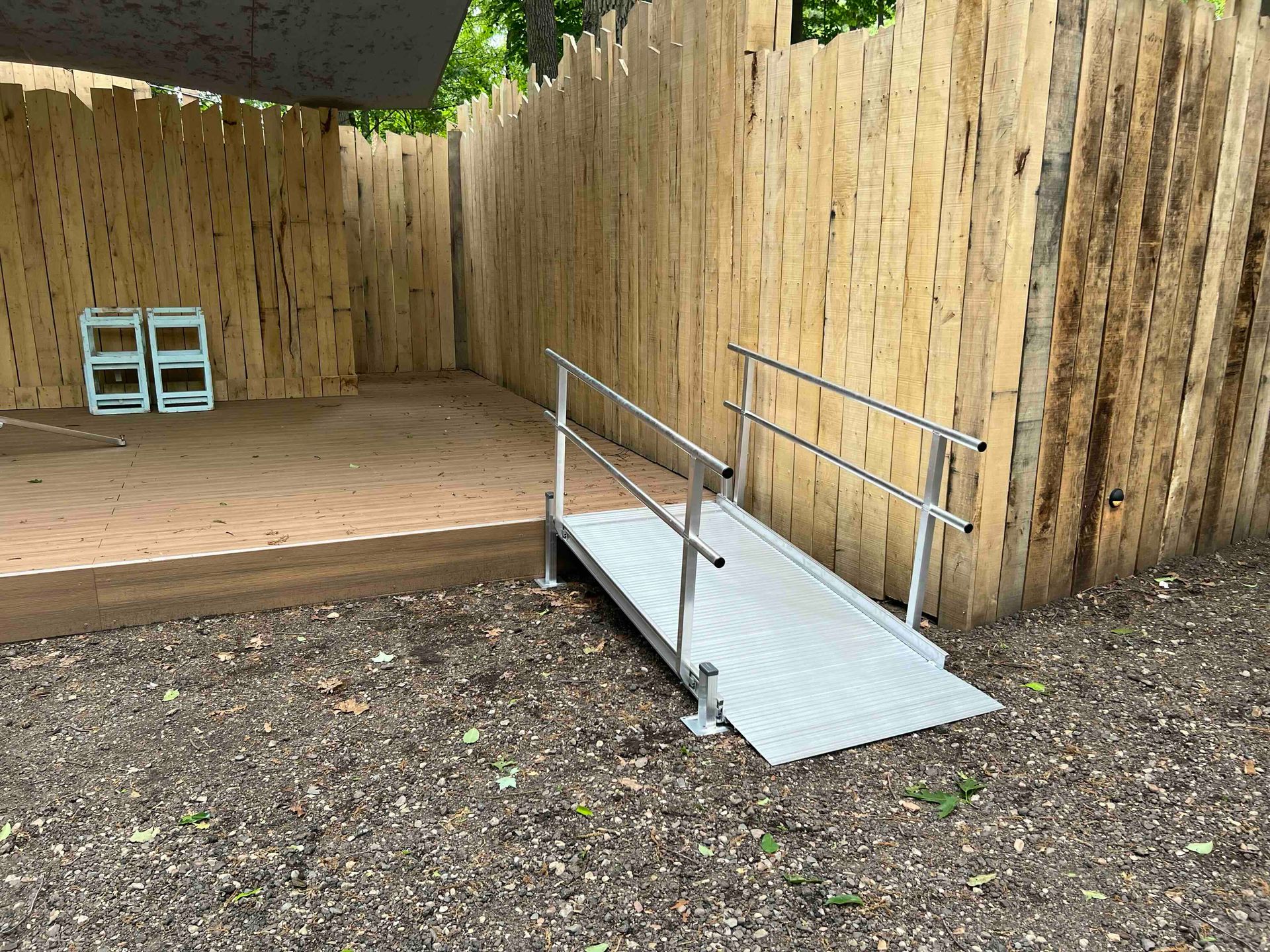 A ramp is sitting in the dirt in front of a wooden fence.