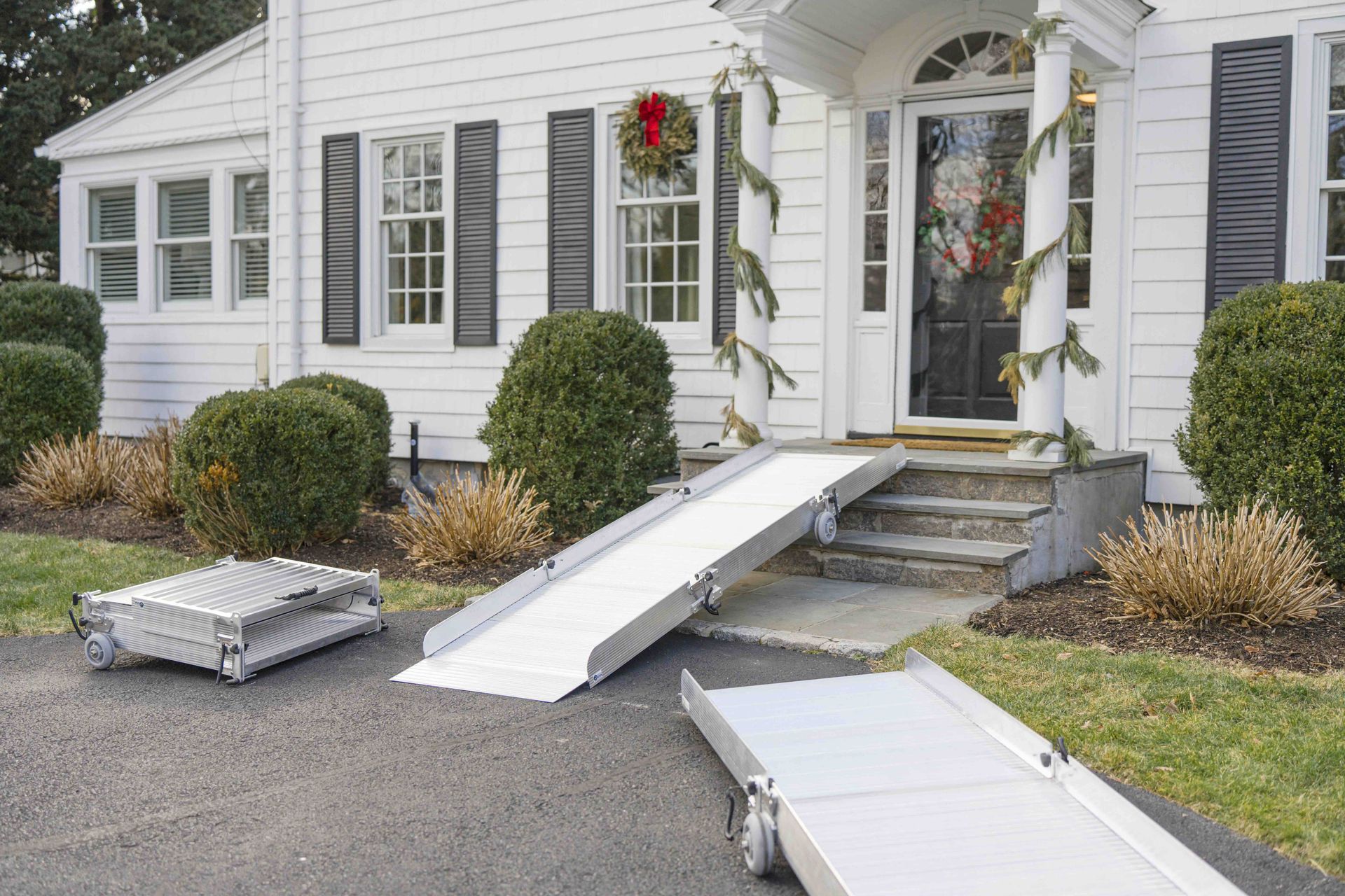 Aluminum ramp leading to a house entrance with Christmas decorations. Two additional ramp sections are visible.