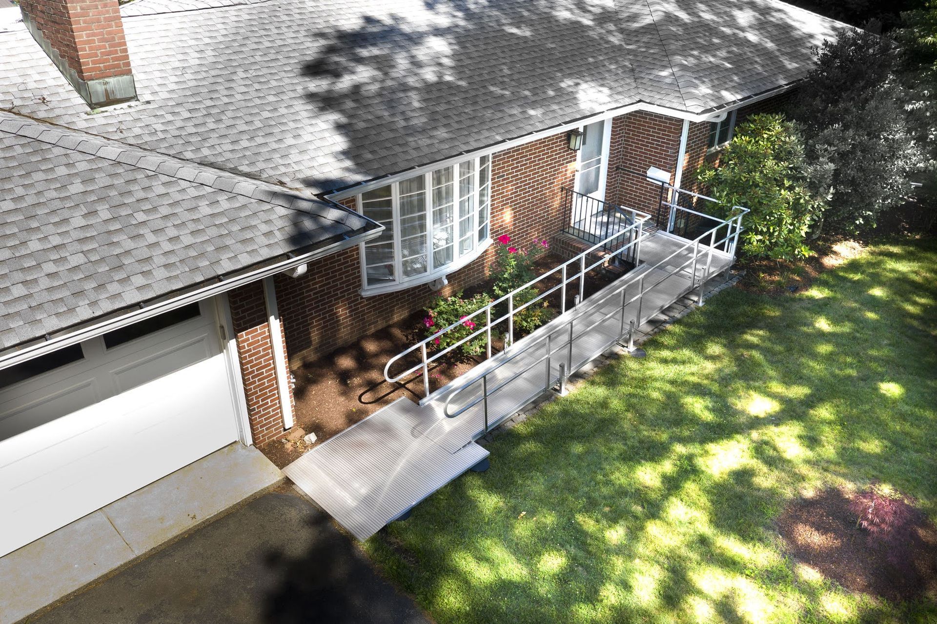 House with a wheelchair ramp leading to the front door, next to a manicured lawn.