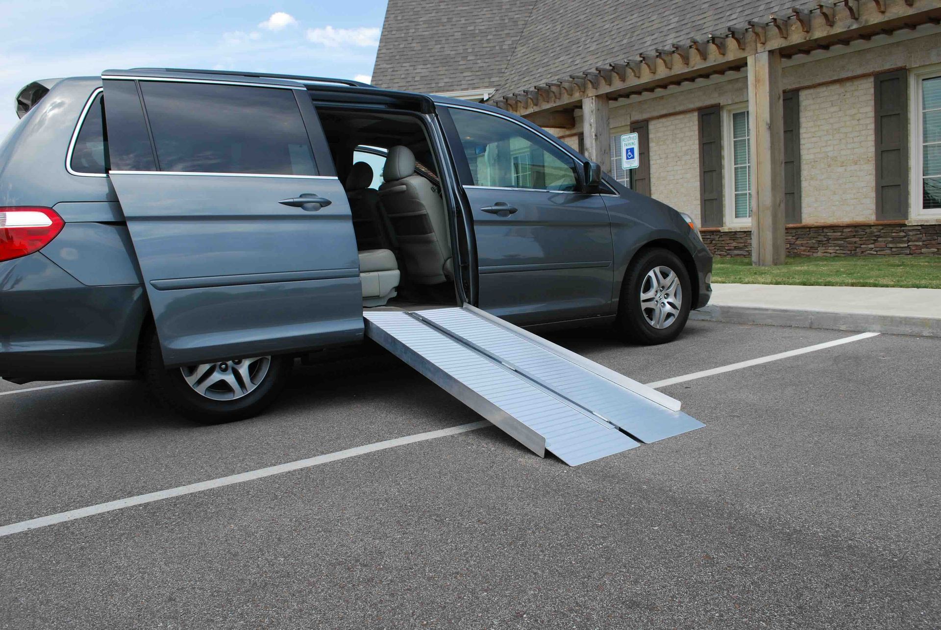 A van with a ramp attached to it is parked in a parking lot.