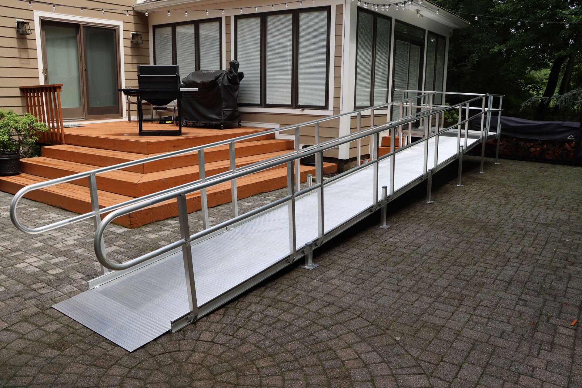 Aluminum ramp with handrails leading to a deck outside a house.