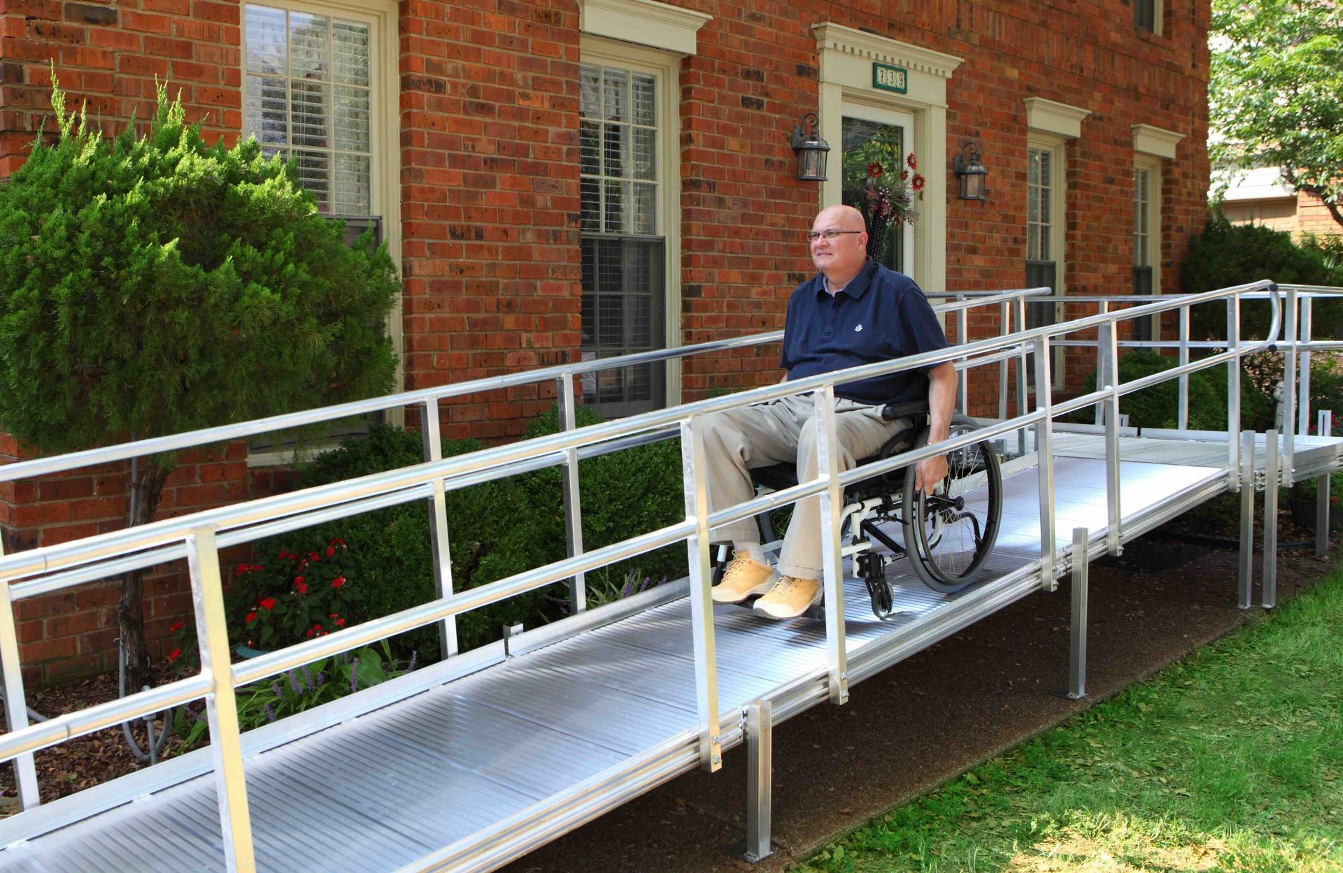 A man in a wheelchair is going down a temporary ramp.