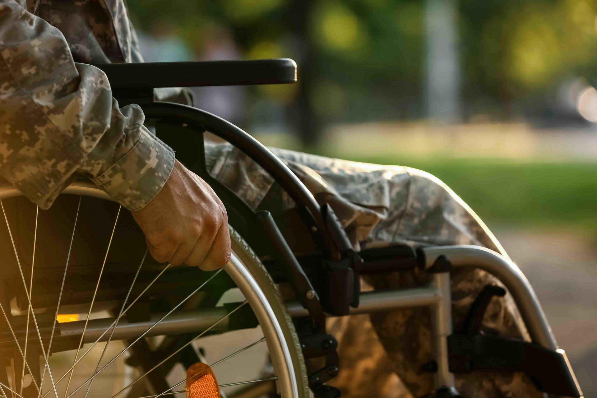 A soldier is sitting in a wheelchair in a park.