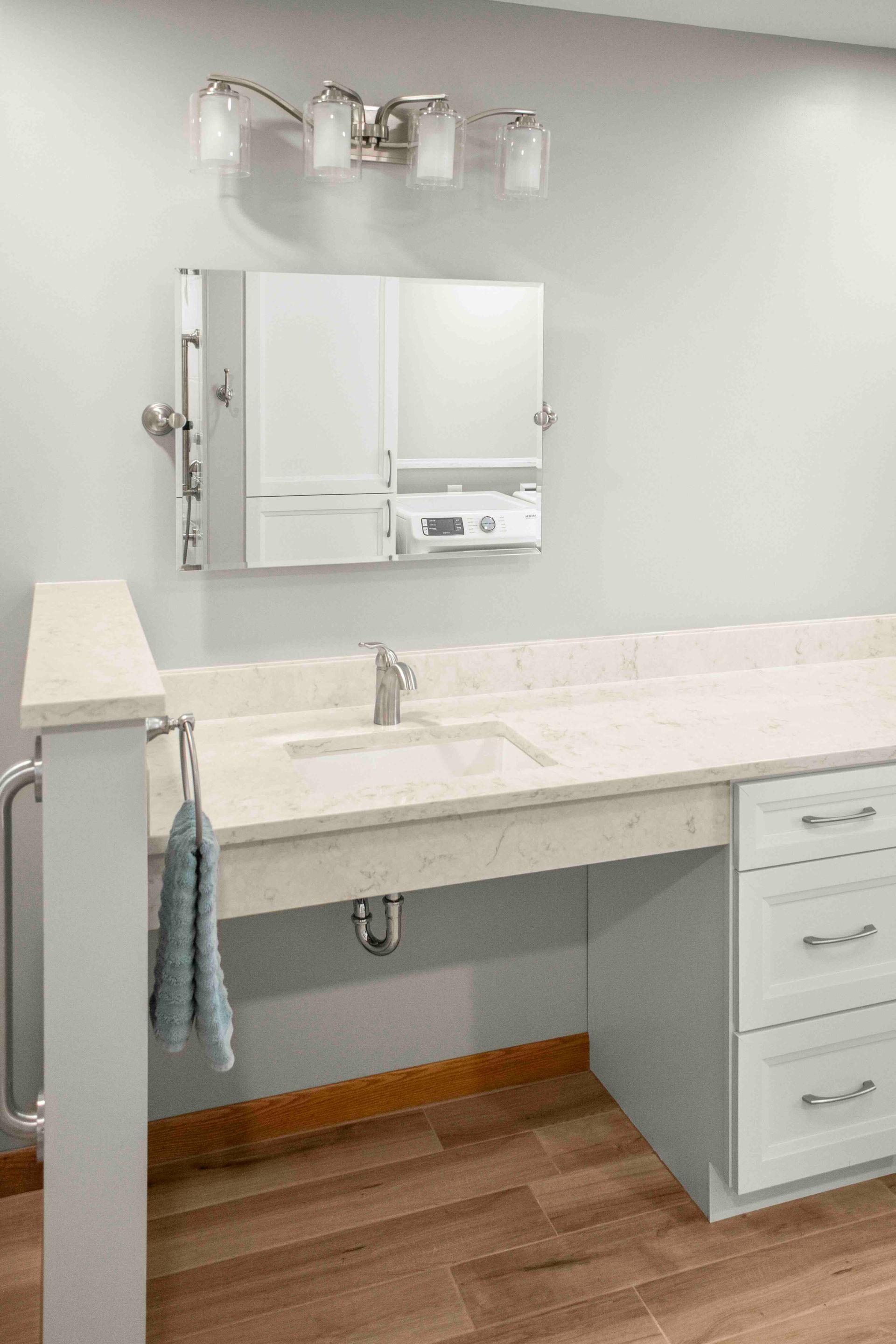 A bathroom with a sink , mirror and drawers.