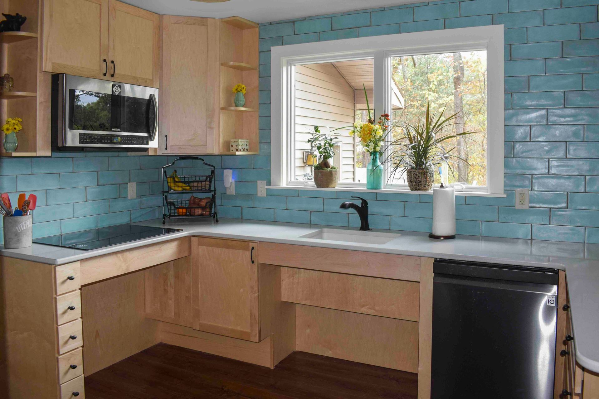 A wheelchair-accessible kitchen with a sink, stove, microwave and window.