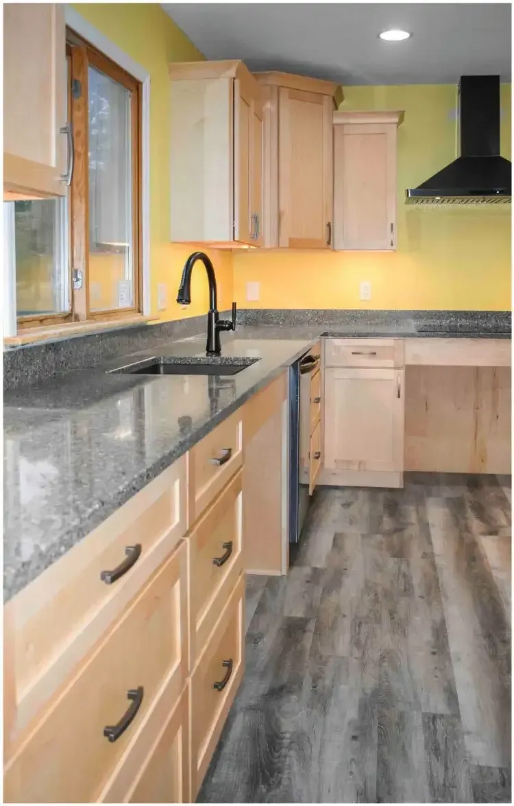 a kitchen with wooden cabinets , granite counter tops , and a sink .