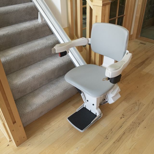 a stair lift is sitting on a wooden floor next to a set of stairs.