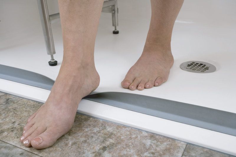 a person is standing in a shower with their feet on the floor.