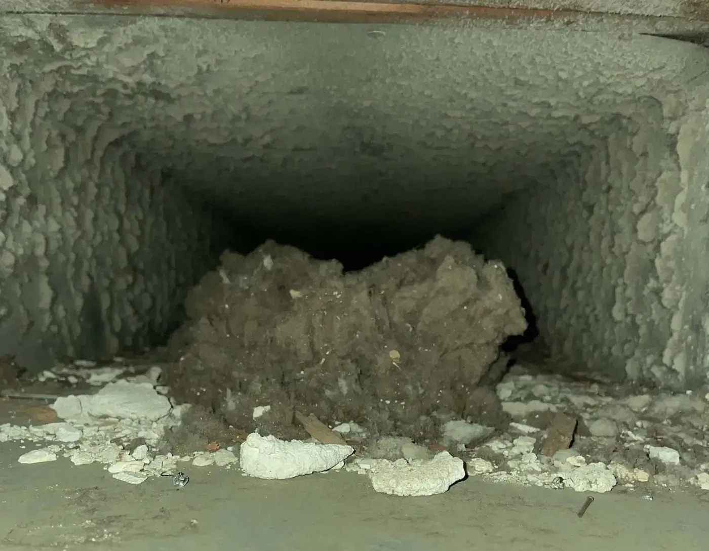 Ductwork interior filled with dust and debris, with a large clump in the center.