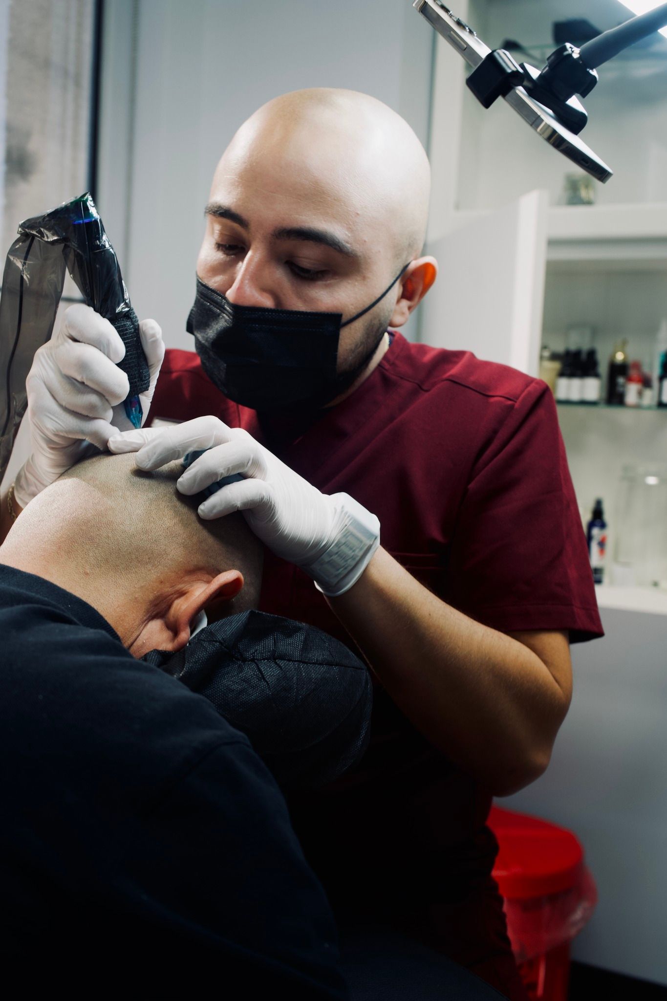 A man is getting a tattoo on another man 's head.