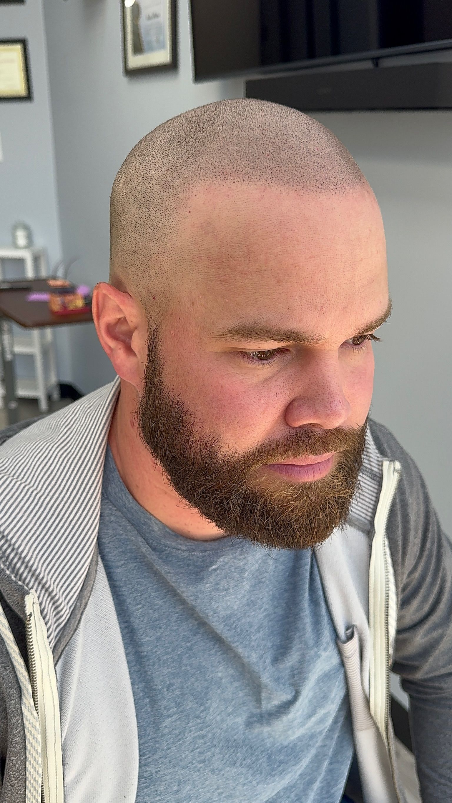 A man with a beard and a bald head is sitting in a room.