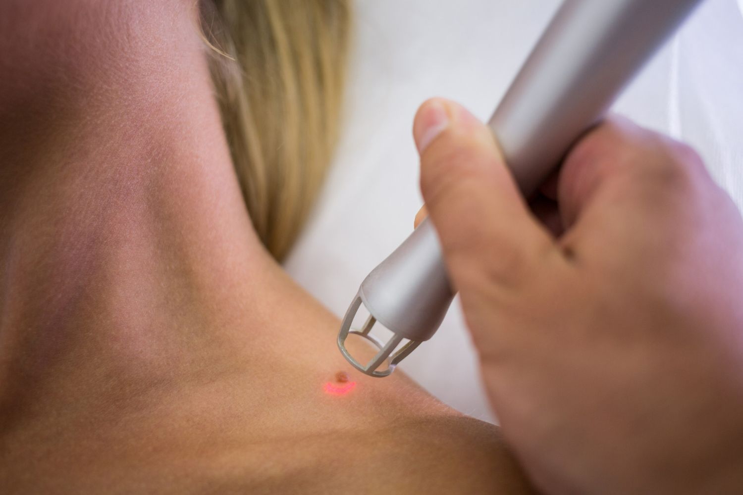 A woman is getting a laser treatment on her neck.