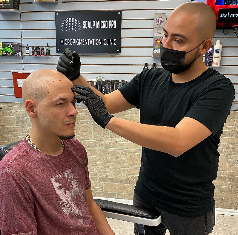 A man is getting his hair cut by a barber wearing a mask and gloves.