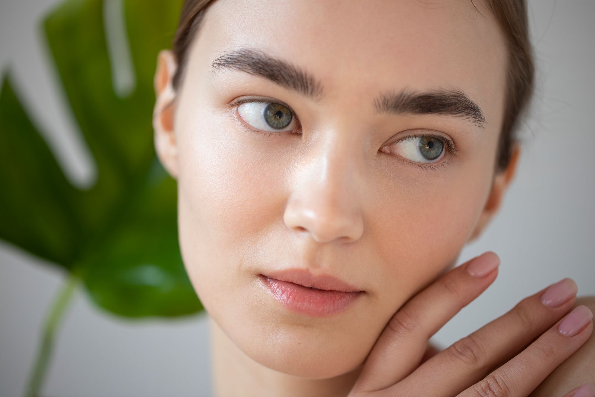 A close up of a woman 's face with a palm leaf in the background.