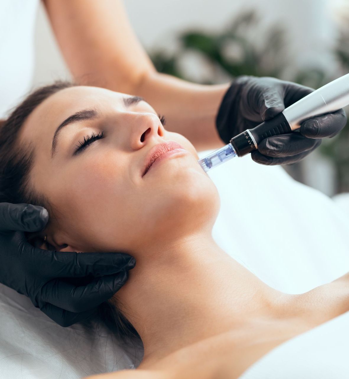 A woman is laying on a bed getting a treatment on her face.