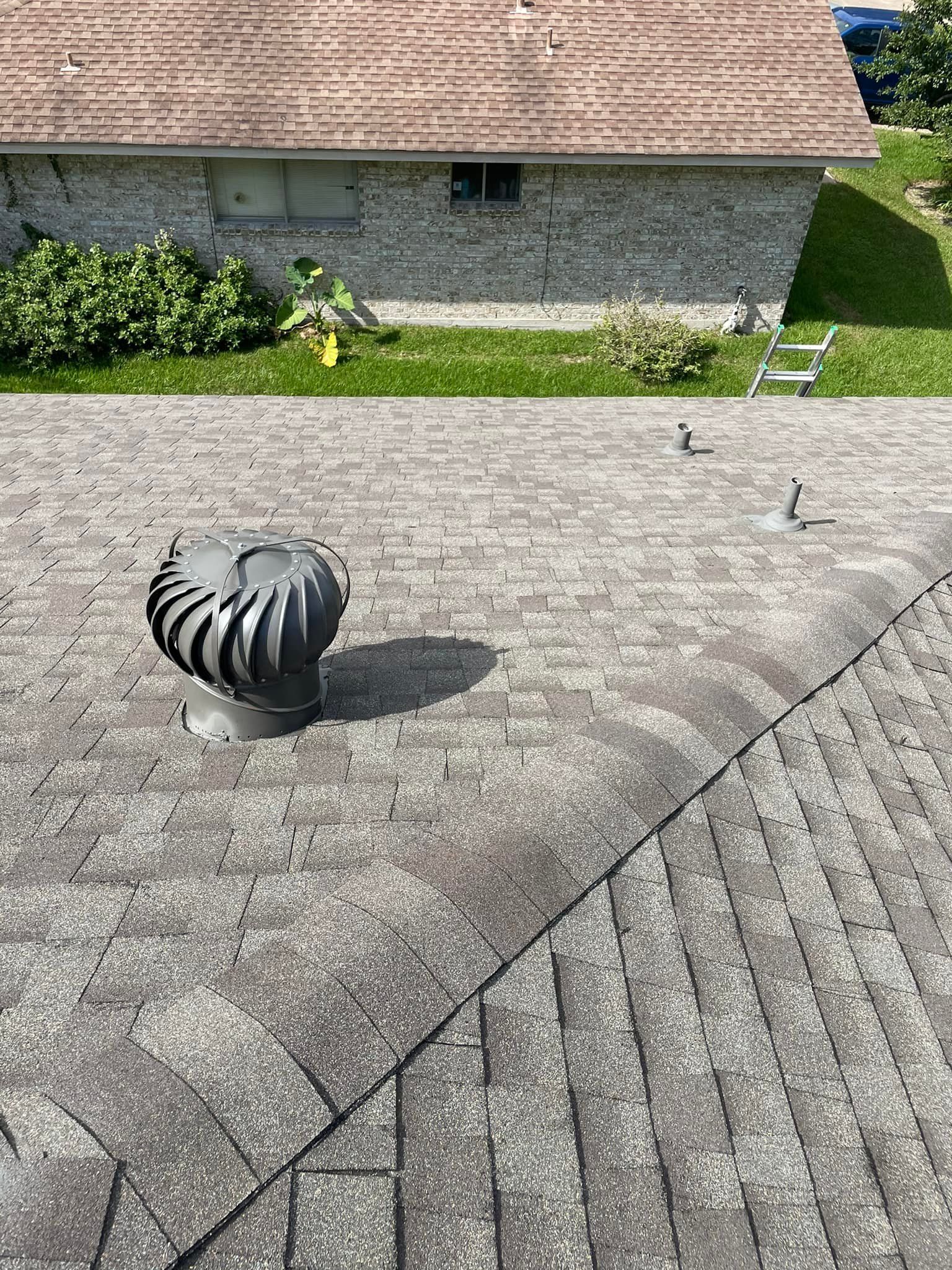 Overhead view of a weathered asphalt shingle roof with a spinning roof vent.