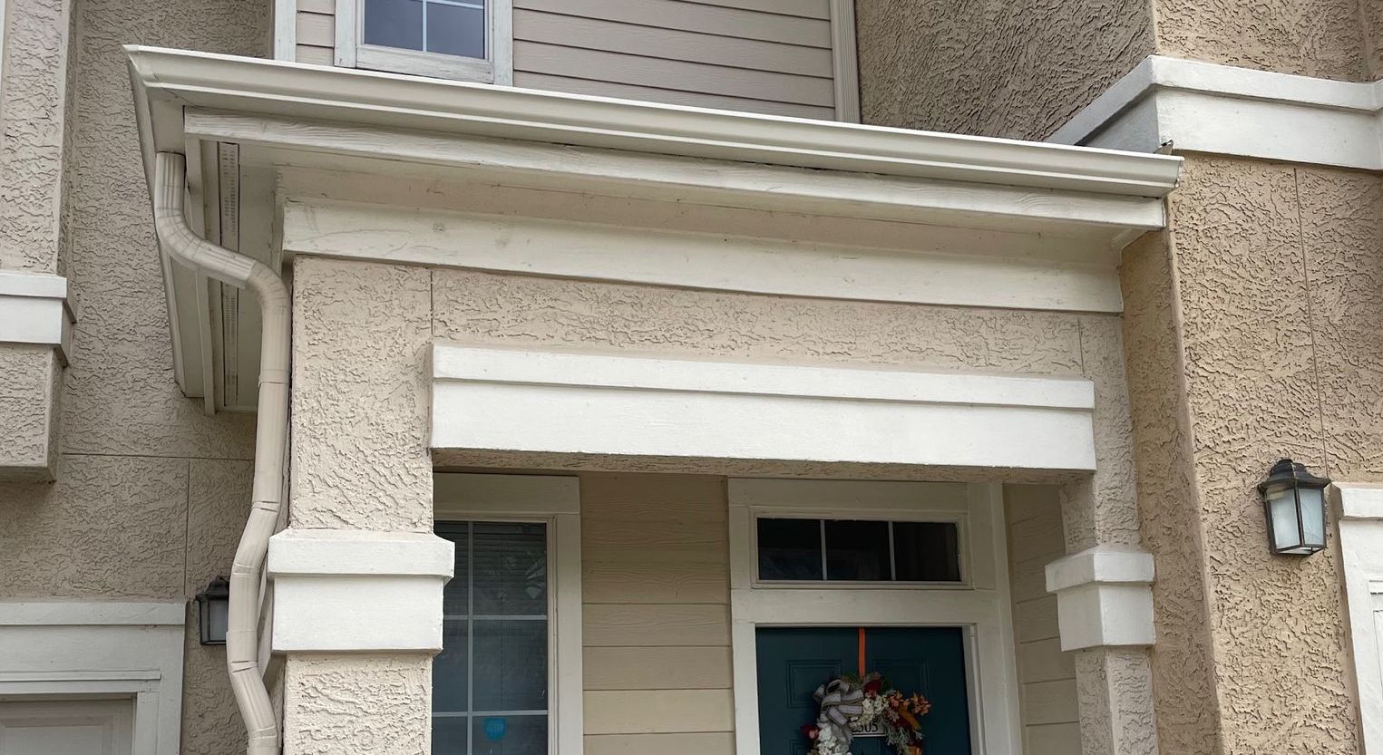 Exterior of a building with a stucco facade, white trim, and a blue front door.