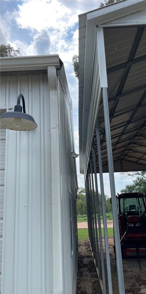 Side view of two adjacent metal buildings. One is white with a black light fixture.