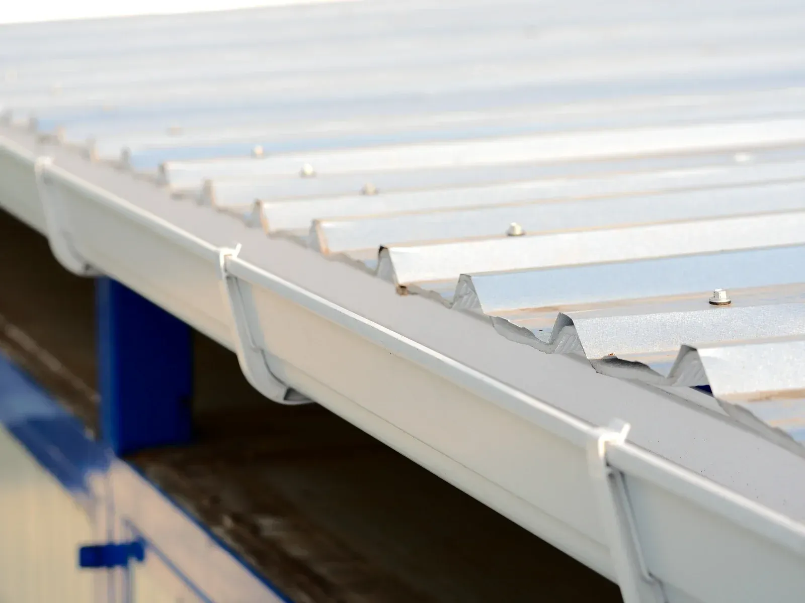 White metal roof with a matching gutter. The roof is angled, reflecting sunlight.