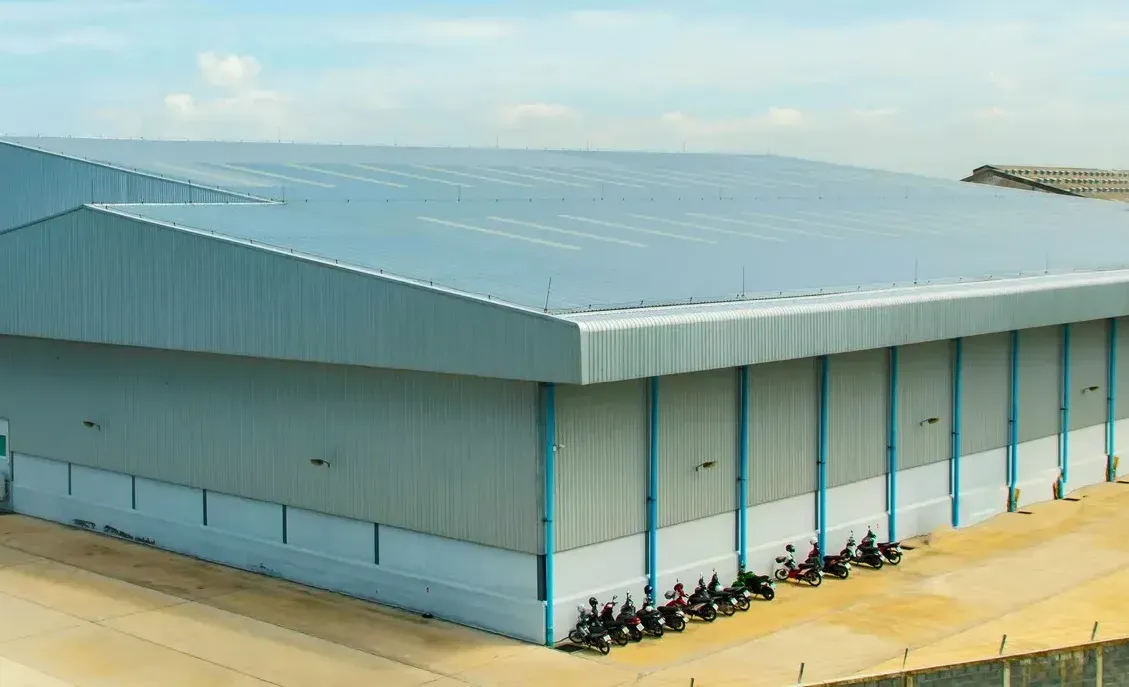 Large industrial building with a gray metal roof and siding, parked motorcycles in front.