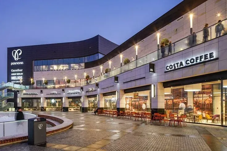 Shopping center exterior with Costa Coffee, gray and black facade, outdoor seating.