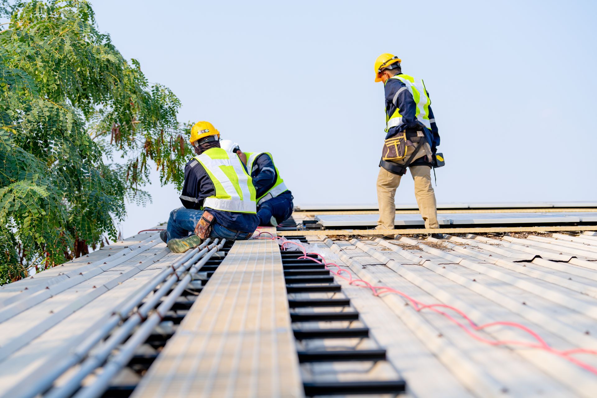 Three people around a table reviewing blueprints, one with a hard hat.