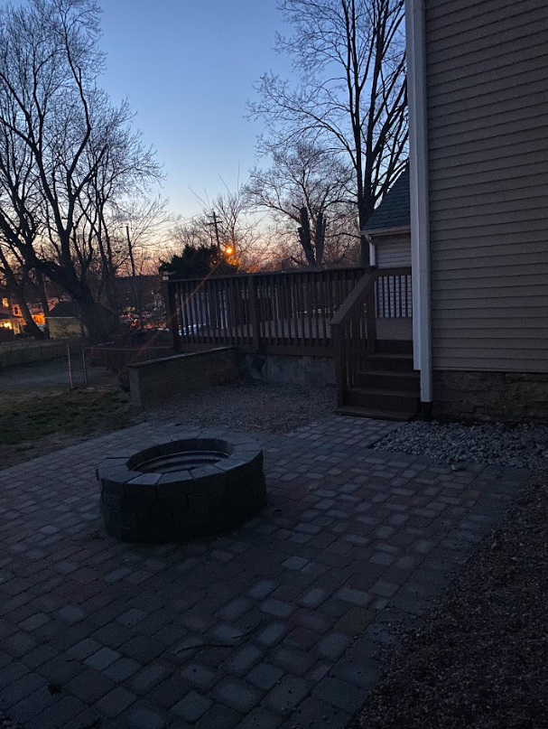 A fire pit on a patio next to a house at sunset.