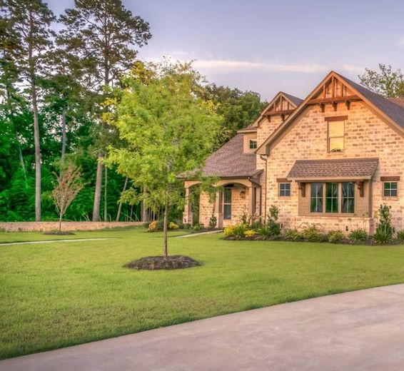 A large brick house with a lush green lawn in front of it.