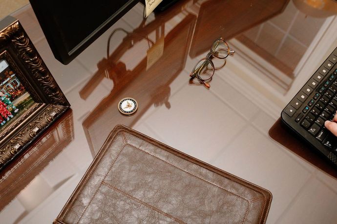 Top-down view of a desk with a pair of glasses, photo frame, keyboard, and padfolio