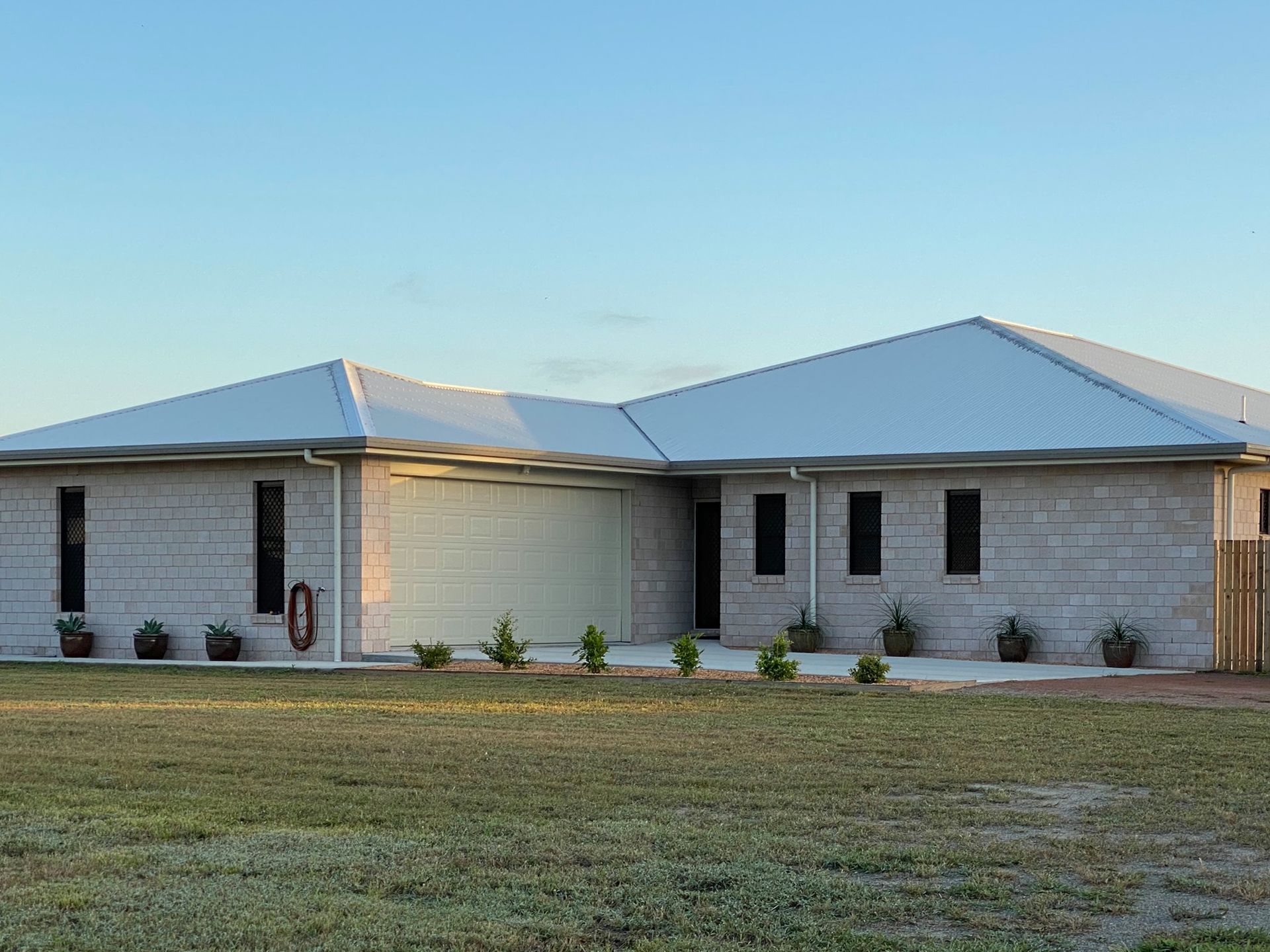 A Modern House With A Large Garage And A Lush Green Lawn — Darryl Tickle Building Pty Ltd In Alice River, QLD