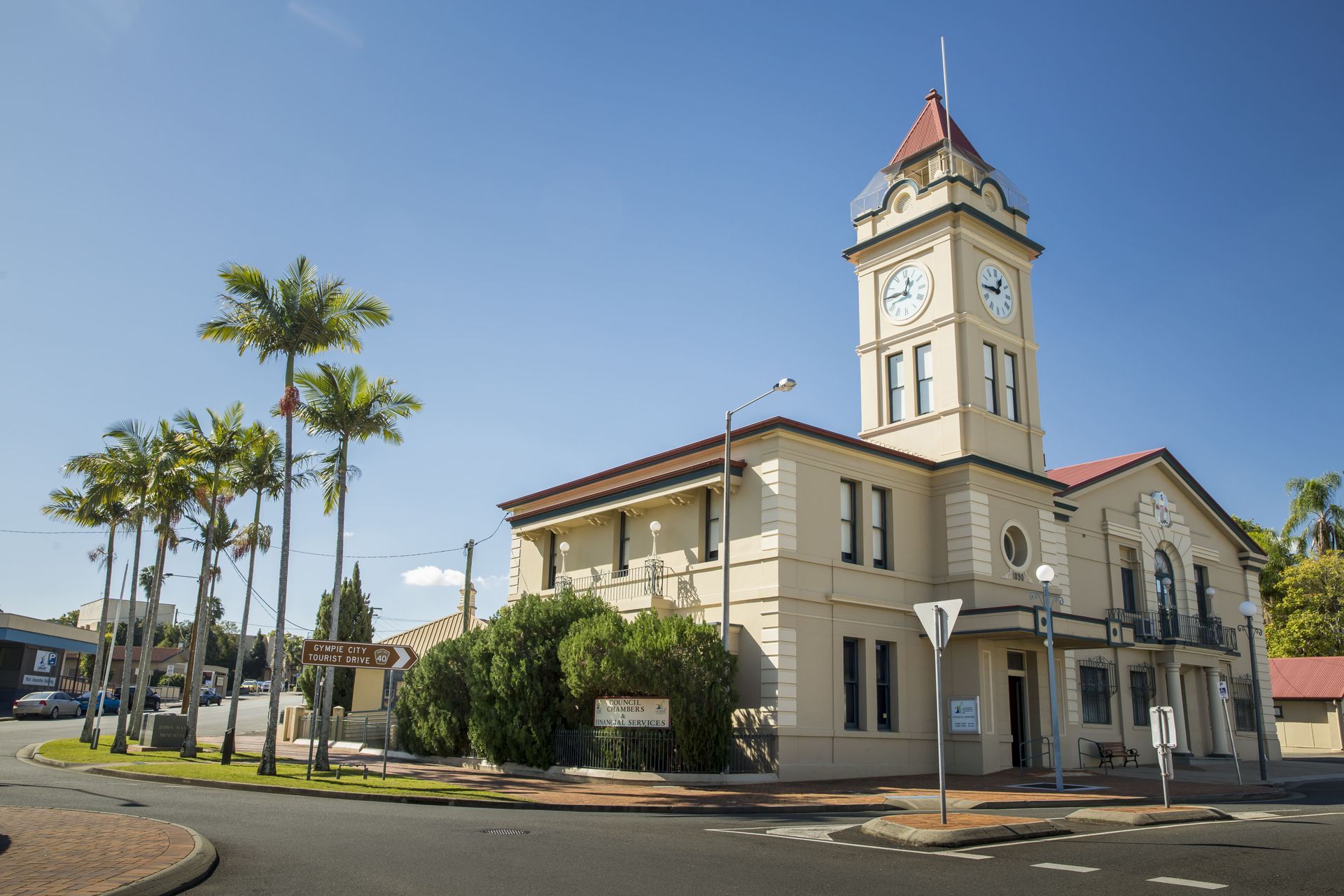 A Cream-colored Building With Clock Tower, Palm Trees — Country To Coast Building Contractors In Gympie, QLD