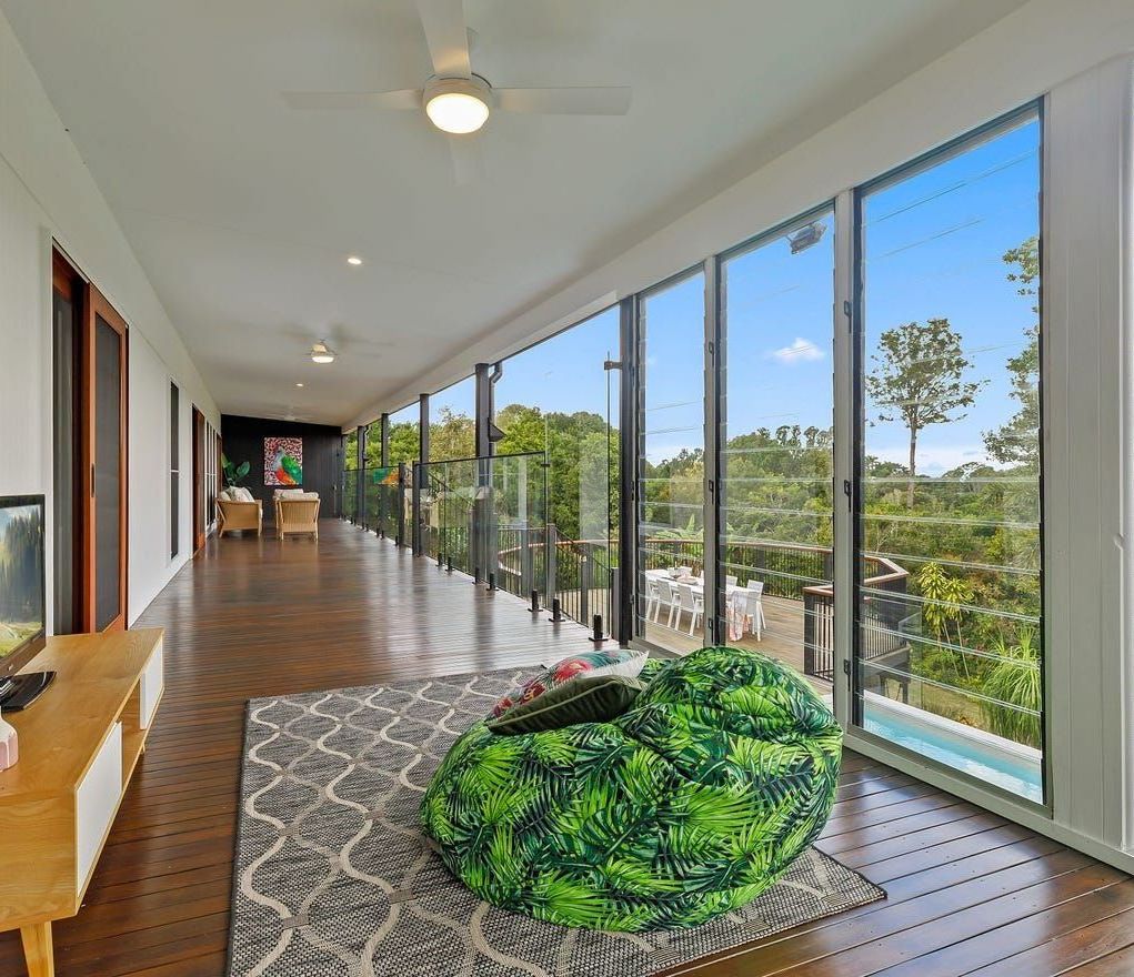 A Living Room With A Lot Of Windows And A Green Bean Bag Chair — Country To Coast Building Contractors In Landsborough, QLD